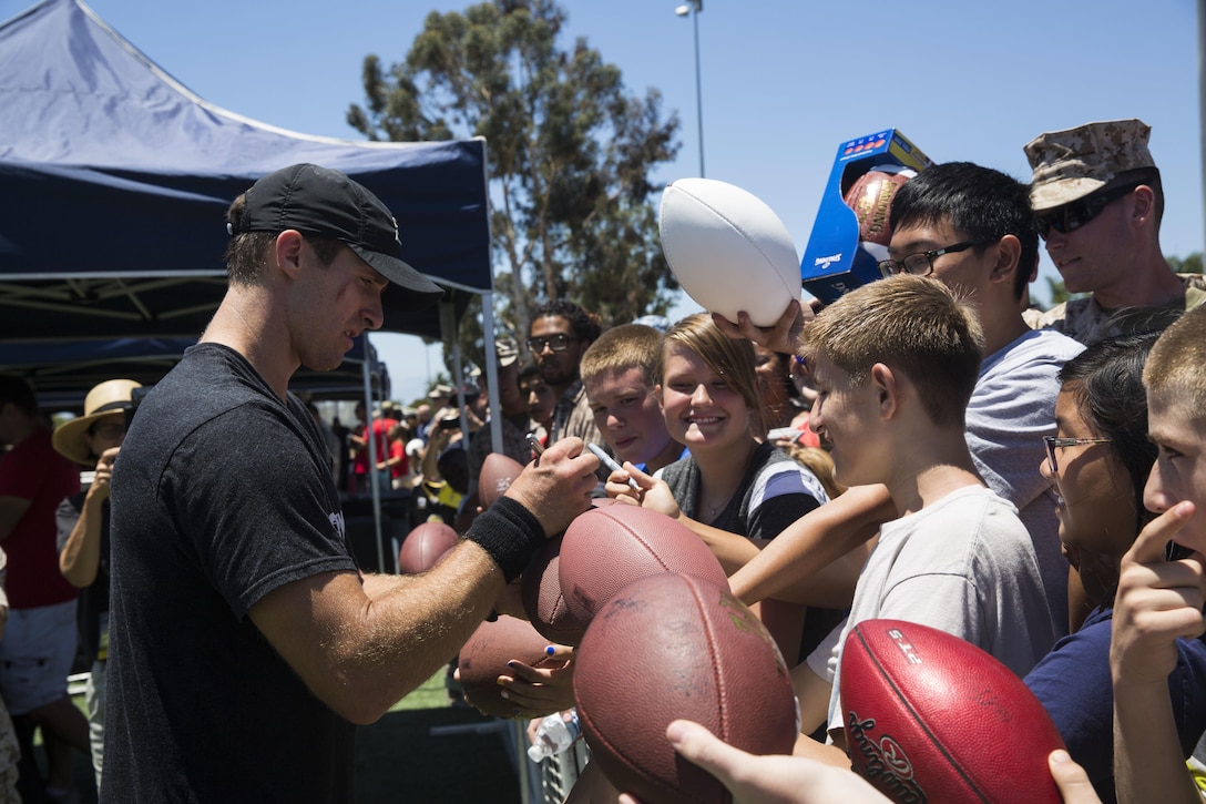 Drew Brees, starting quarterback for the New Orleans Saints, signs autographs for station residents after the National Football League Star Experience at Marine Corps Air Station Miramar, California, July 14. NFL players who train with Todd Durkin, a professional performance-enhancement coach and personal trainer, practiced with the Miramar Falcons football team and interacted with service members and families. (U.S. Marine Corps photo by Cpl. Alissa P. Schuning/Released)