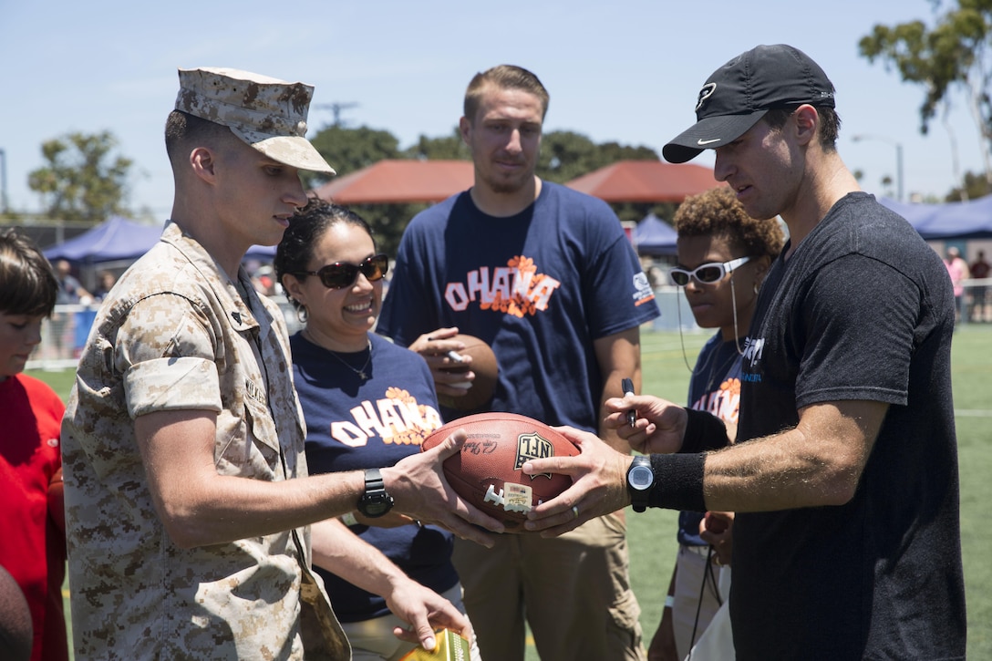 Drew Brees, starting quarterback for the New Orleans Saints, signs autographs for station residents after the National Football League Star Experience at Marine Corps Air Station Miramar, California, July 14. NFL players who train with Todd Durkin, a professional performance-enhancement coach and personal trainer, practiced with the Miramar Falcons football team and interacted with service members and families. (U.S. Marine Corps photo by Cpl. Alissa P. Schuning/Released)