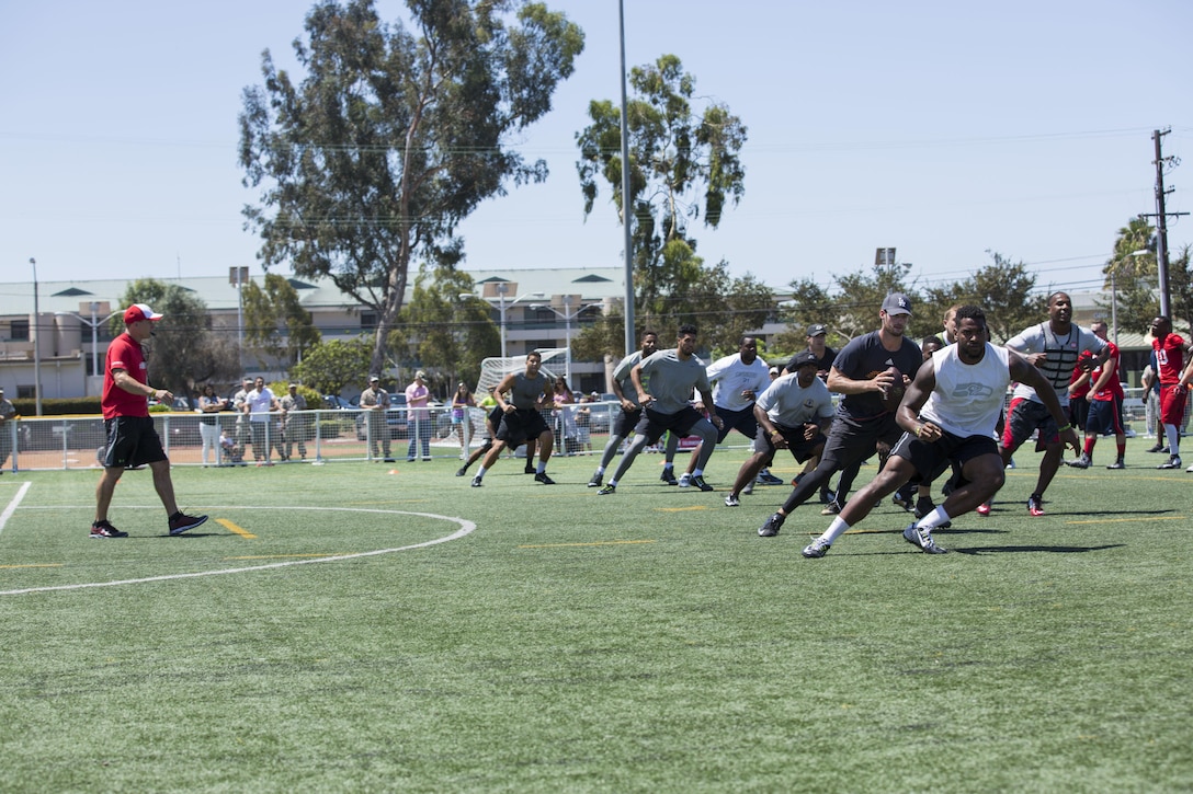 National Football League players run through drills led by Todd Durkin, a professional performance-enhancement coach and personal trainer, during the NFL Star Experience at the Marine Corps Air Station Miramar Sports Complex, July 14. The football players practiced with the Miramar Falcons football team and interacted with service members and families. (U.S. Marine Corps photo by Cpl. Alissa P. Schuning/Released)