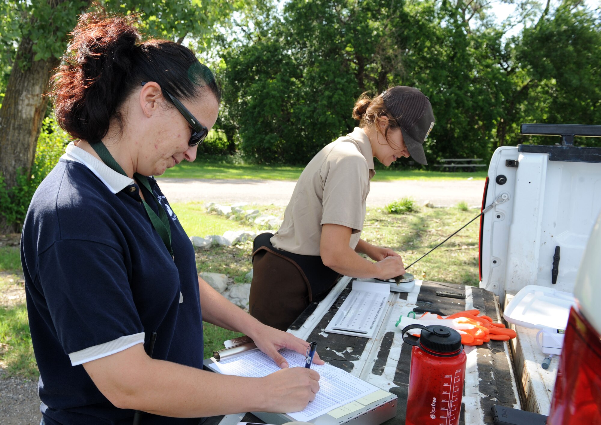 Lauren Caister, Bird/Wildlife Aircraft Strike Hazard program manager, helps catalog fish size and weight with a U.S. Fish and Wildlife Service biologist, July 15, 2015, at McConnell Air Force Base, Kan. The two programs work together to prevent the spread of invasive species and control wildlife population. (U.S. Air Force photo by Senior Airman David Bernal Del Agua)