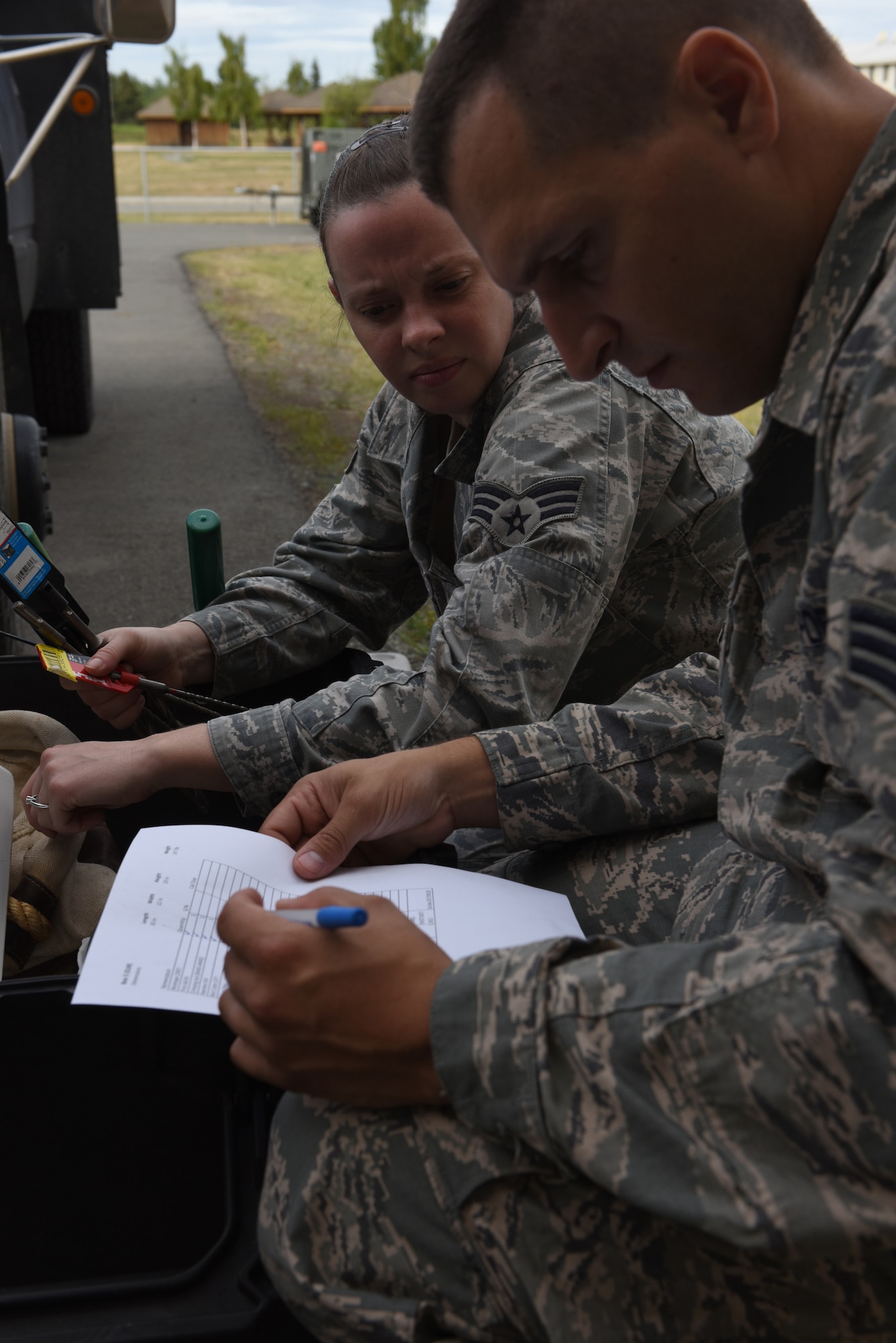 Senior Airman Matthew Gold, cable and antenna systems technician, 211th Engineering Installation Squadron, reviews the supply list with Senior Airman Holly Miller, airfield systems technician, as they take inventory of their equipment on the first day of Exercise Frosty Spear.  These Airmen will be helping to complete radio-antenna grounding projects for seven different buildings on Joint Base Elmendorf-Richardson, Anchorage, Alaska. (U.S. Air National Guard photo by Staff Sgt. Claire Behney/Released)