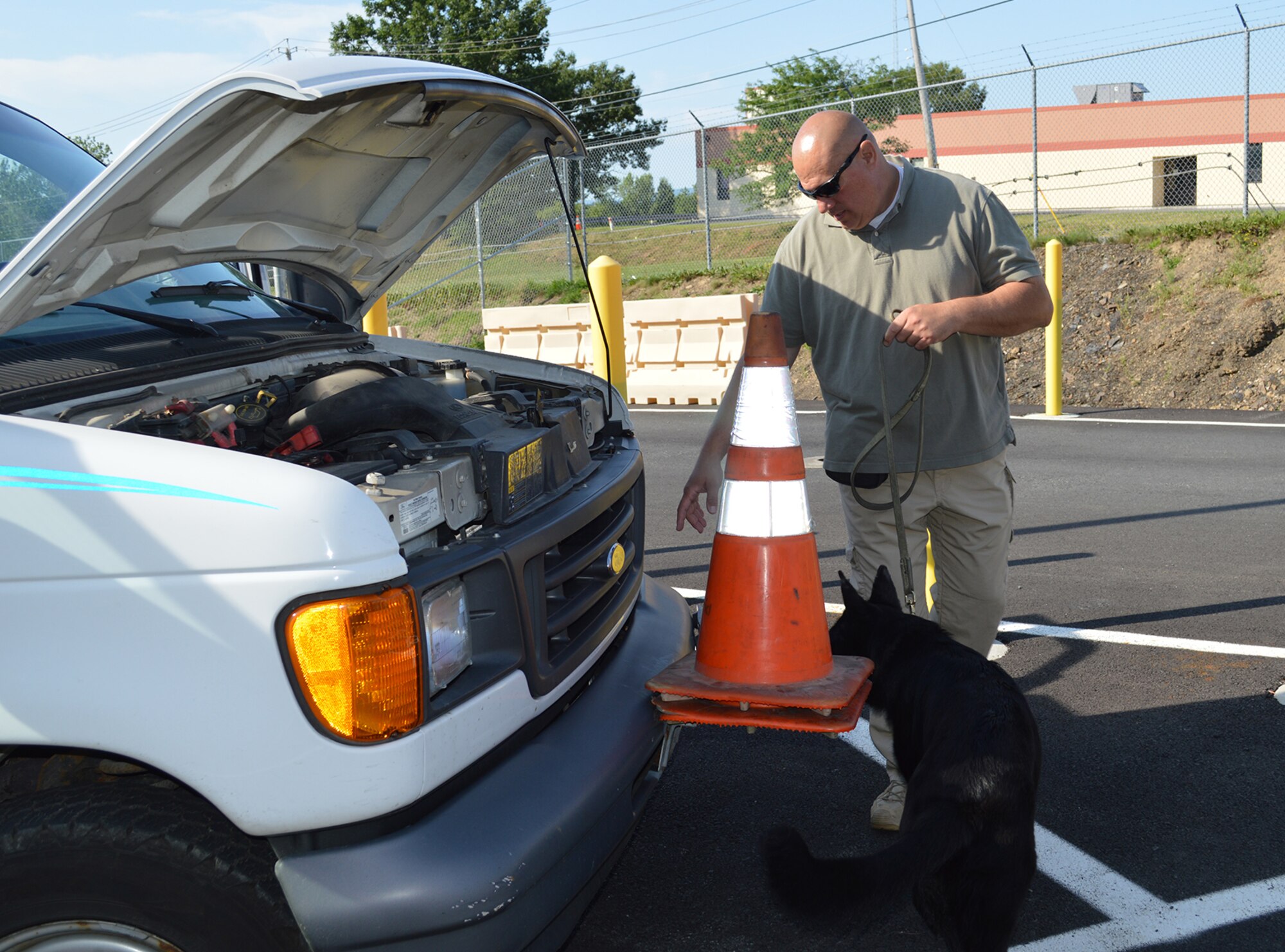 Tech. Sgt. Scott Everson and Aggie search a vehicle at the front gate on July 16, 2015, at Stratton Air National Guard Base, New York. Everson, a loadmaster with the 139th Airlift Squadron, works as a K-9 handler in a private security company on the civilian side with Aggie, an explosive detection K-9. Everson was given approval by 109th Airlift Wing leadership to train Aggie at the base, giving the 109th Security Forces Squadron an added measure of security at the front gate. Aggie will be assisting with random vehicle inspections over the next few months while at the same time receiving real-world training. (U.S. Air National Guard photo by Tech. Sgt. Catharine Schmidt/Released)