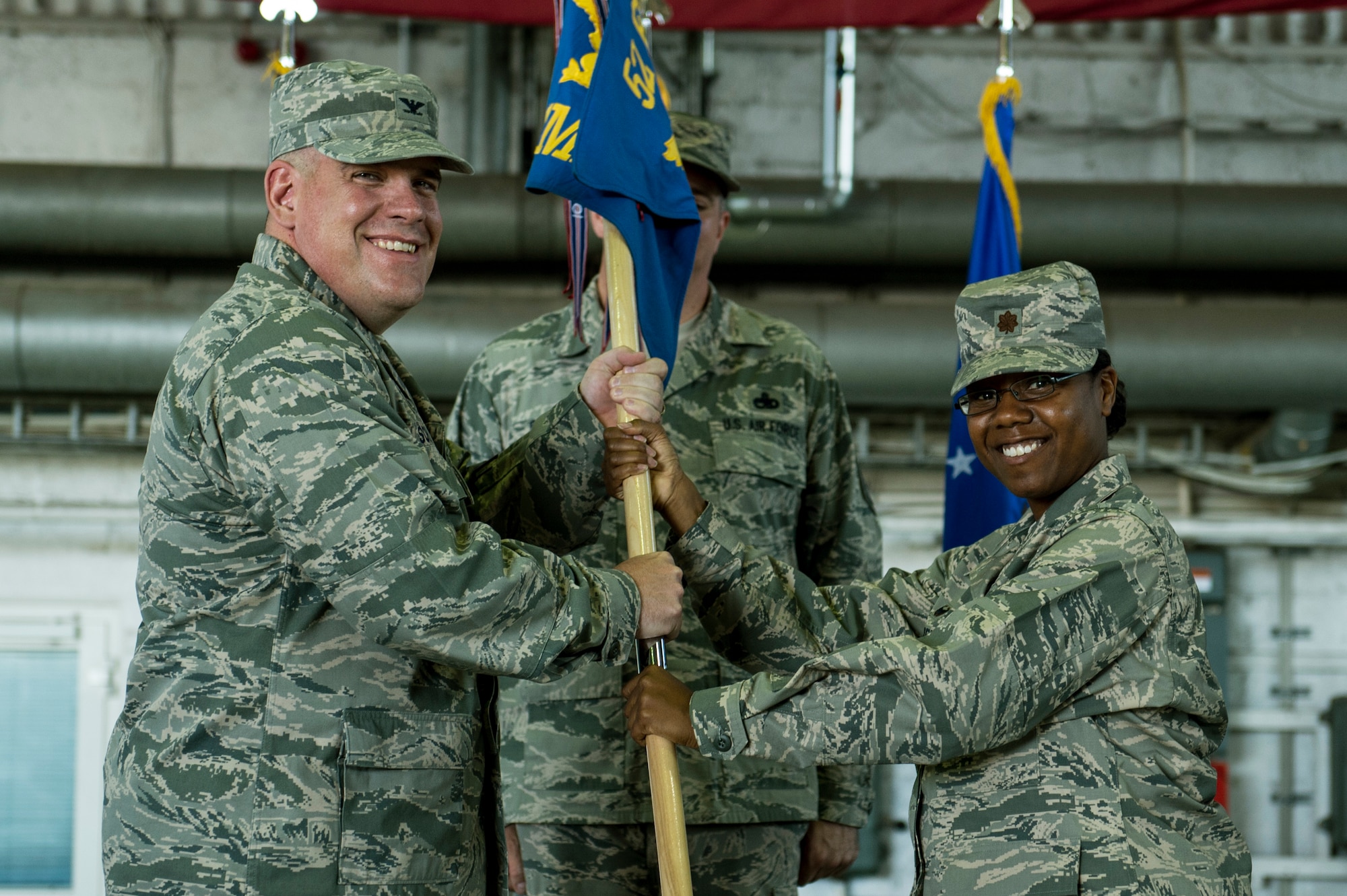 U.S. Air Force Col. Stephen Scherzer, 52nd Maintenance Group commander left, hands the ceremonial guidon to U.S. Air Force Maj. Strysan Murrell, the incoming 52nd Component Maintenance Squadron commander, during the 52nd CMS change of command ceremony inside Hangar 2 on Spangdahlem Air Base, Germany, July 16, 2015. Bradley assumed command from former commander, U.S. Air Force Maj. David Marce. (U.S. Air Force photo by Senior Airman Rusty Frank/Released)