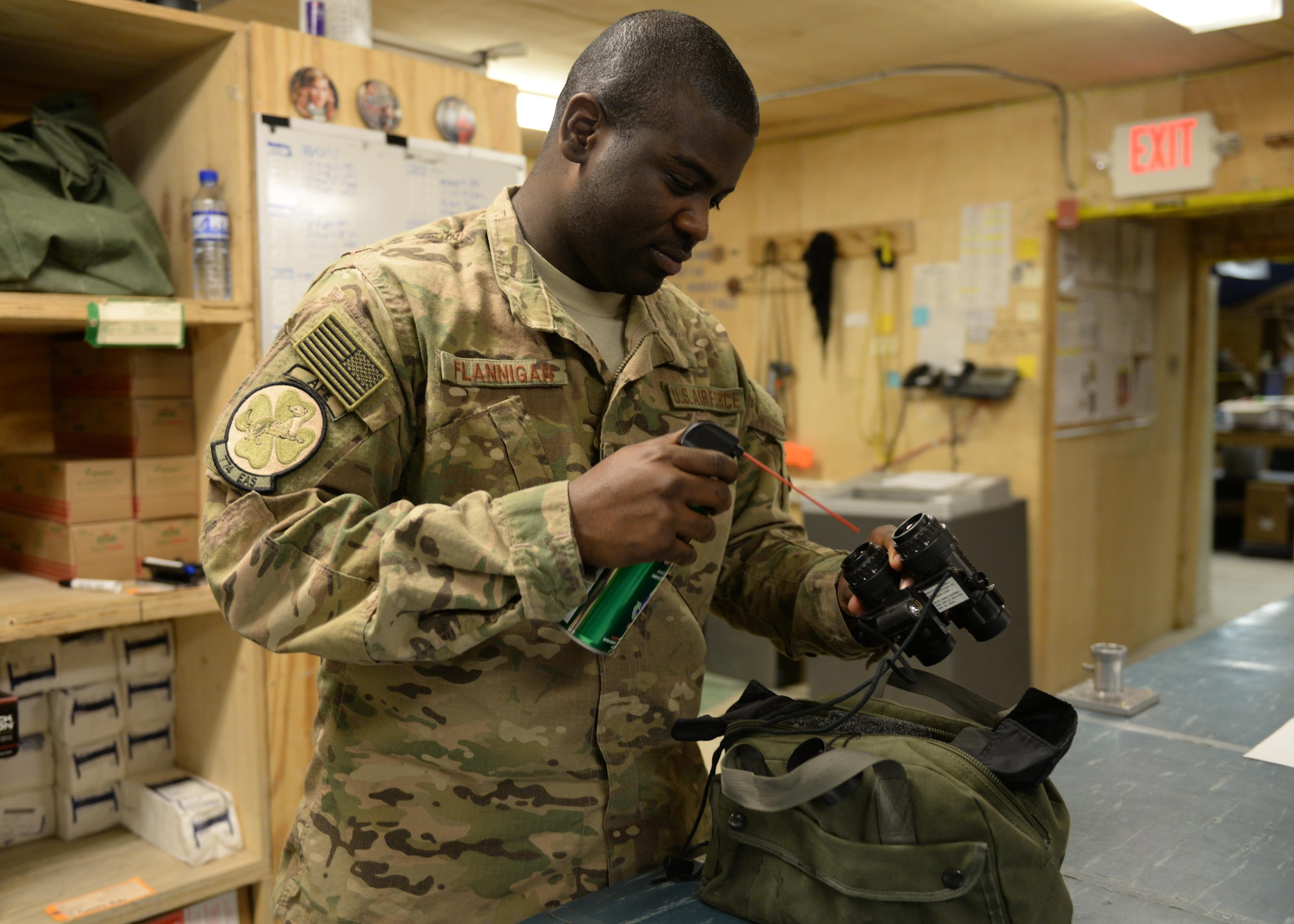 U.S. Air Force Senior Airman Greg Flannigan, 455th Expeditionary Airlift Squadron aircrew flight equipment journeyman, cleans a pair of binoculars before issuing them to a C-130 aircrew member July 17, 2015, at Bagram Airfield, Afghanistan. Flannigan is responsible for making sure aircrews are supplied with lifesaving equipment prior to flying a mission here. (U.S. Air Force photo by Senior Airman Cierra Presentado/Released)