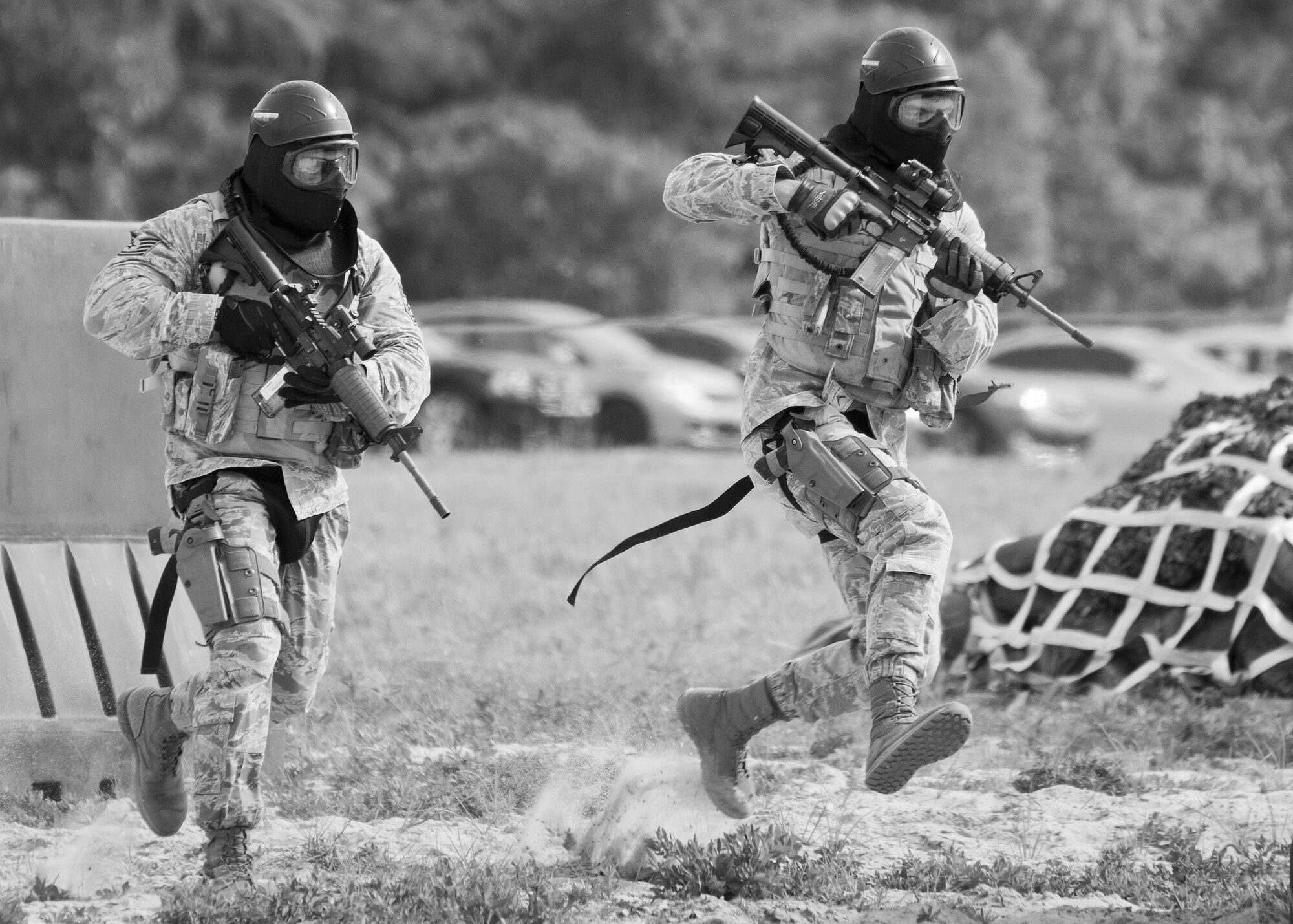 Two Airmen from the 96th Security Forces Squadron Airman run for cover during a shoot, move and communicate drill at Eglin Air Force Base, Fla, June 23, 2015. The mandatory training requirement is in addition to annual weapons qualification training. The exercise consists of Airmen firing simmunition ammo while advancing toward, away from and to the side of a target. This is followed by a building sweep and clear drill. The Defenders perform the highly kinetic training at Eglin’s Base Tango range. The range was previously used for security forces pre-deployment training. (U.S. Air Force photo/Samuel King Jr.)