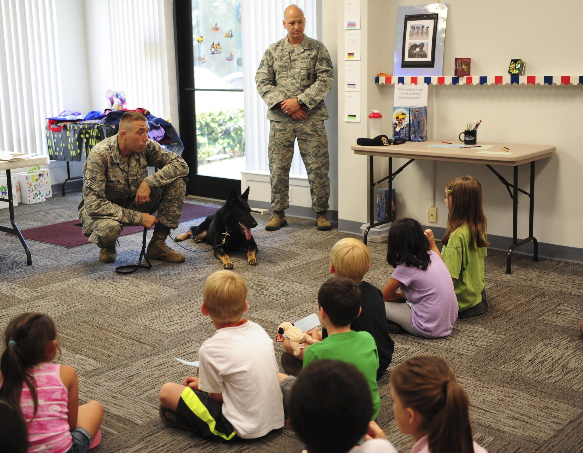 Staff Sgt. Ryan Troester, 1st Special Operations Security Forces Squadron military working dog trainer, speaks with children at the Mary Esther public library, July 15, 2015, in Mary Esther, Fla. The library hosted a Military Animal Heroes event as part of their Summer Reading Program and Hurlburt Field’s K9 unit was invited to come speak about their profession.  (U.S. Air Force photo/Senior Airman Meagan Schutter)