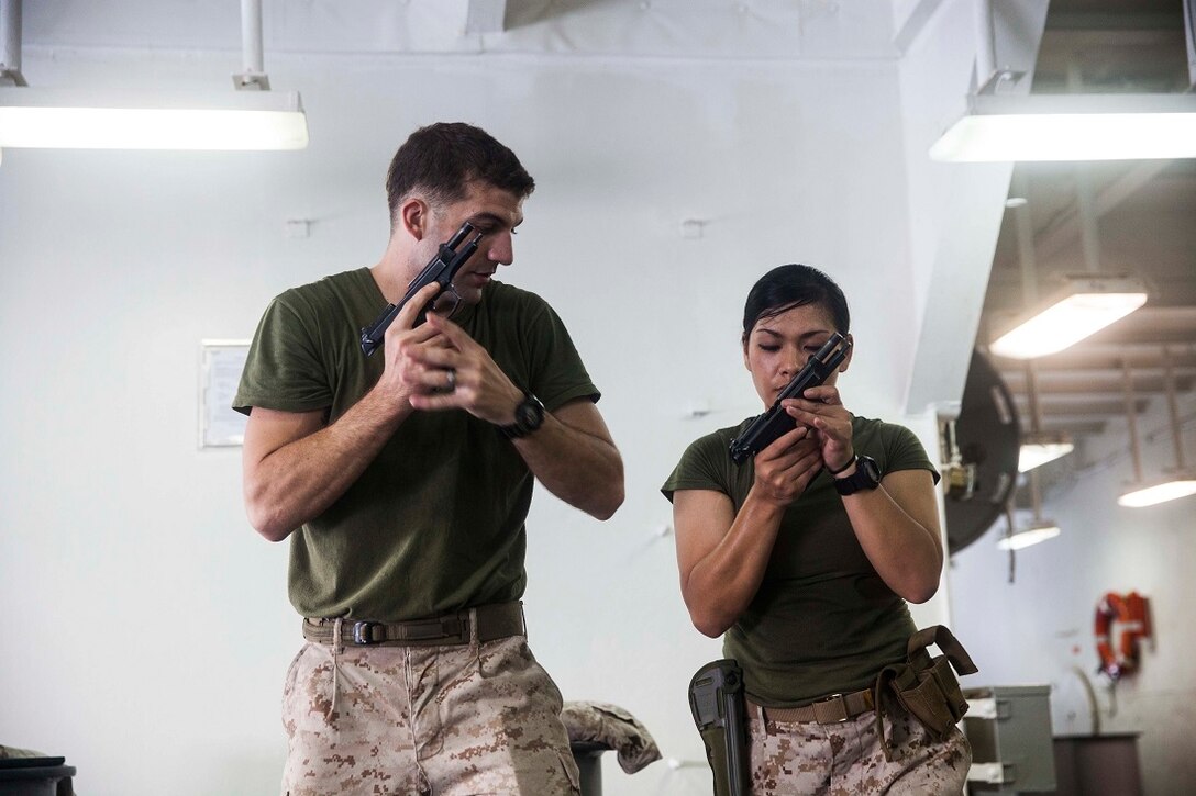 GULF OF ADEN (July 9, 2015) U.S. Marine Sgt. Erik Maehler, left, demonstrates loading a M9 Beretta pistol to Hospital Corpsman 1st Class Sunshine Padilla aboard the amphibious assault ship USS Essex (LHD 2). Maehler is a member of the 15th Marine Expeditionary Unit’s Maritime Raid Force and Padilla is a hospital corpsman with Marine Medium Tiltrotor Squadron 161 (Reinforced), 15th MEU. The Marines practice marksmanship fundamentals dry to ensure safety and accuracy when shooting. The 15th MEU is embarked on the Essex Amphibious Ready Group and deployed to maintain regional security in the U.S. 5th Fleet area of operations. (U.S. Marine Corps photo by Cpl. Anna Albrecht/Released)