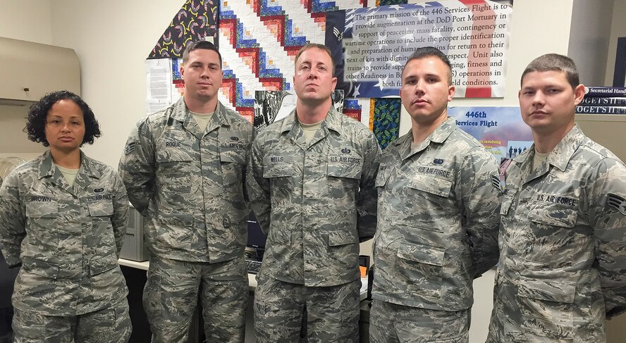 From left, Senior Airman Leatha Brown, Senior Airman Jeremy Roque, Tech. Sgt. Loren Wells, Senior Airman Nathaniel Engen, and Senior Airman Seth Ruble, all services specialists from the 446th Force Support Squadron, pose for a photo in from of mortuary affairs memorabilia here, July 14. All five Airmen will deploy this weekend for what could be the unit’s last opportunity to support Air Force Mortuary Affairs Operations at Dover Air Force Base, Delaware. 