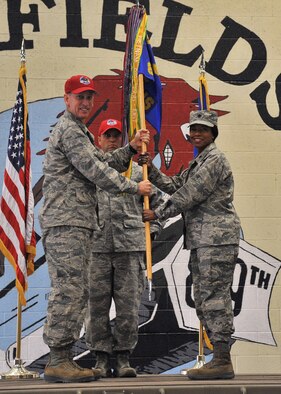 Lt. Col. Yvonne Spencer, right, accepts command of the 819th  RED HORSE squadron from Col. Scott Caine, 9th Air Force vice commander, left, July 17, 2015, at the Airfields hangar on Malmstrom Air Force Base, Mont. Guidon bearer Master Sgt. Robert Jenkins, 819th RHS unit training manager, center, looks on. (U.S. Air Force photo/John Turner)