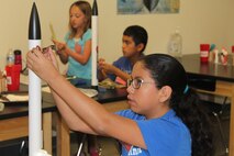 Victoria Villareal, daughter of Master Sgt. Arnold Villareal, 433rd Aircraft Maintenance Squadron, attaches a decal to her rocket on the final morning of a week-long class at DoD STARBASE-Kelly, Joint Base San Antonio-Lackland, Texas on July 17, 2015. Victoria, along with 19 other students, successfully launched rockets later that morning. (U.S. Air Force photo/Tech. Sgt. Carlos J. Trevino) 