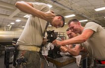 U.S. Air Force Senior Airmen Adam Michaud, left, and David Lee, 23d Equipment Maintenance Squadron combat armament system team members, and Staff Sgt. Chad Ufholz, 23d EMS weapons armament system craftsman, fix a 30mm GAU-8/A gatling gun ammunition drum drive assembly July 11, 2015, at Moody Air Force Base, Ga. The weekend crew works eight-hour days on Mondays and Fridays and 12-hour days on Saturdays and Sundays. (U.S. Air Force photo by Airman 1st Class Ceaira Tinsley/Released)