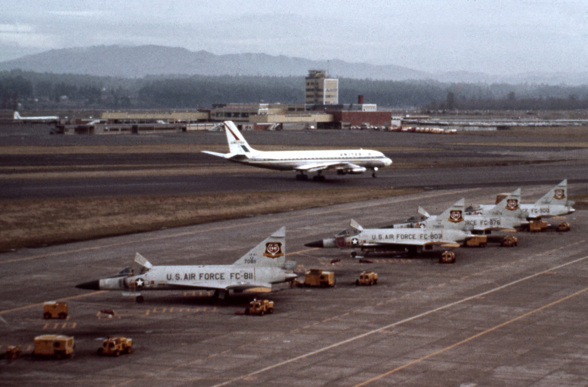 A row of F-102 Delta Daggers assigned to the 337th Fighter Group stand ready at the Portland Air Force Base, Ore., as a commercial aircraft taxis along a shared runway at the Portland International Airport. The photograph was taken in the early 1960’s when the 337th shared the alert mission with the 142nd Fighter Group prior to the official transfer of the aircraft and full time alert mission to the 142nd on April 1, 1966. (photo courtesy of the 142nd Fighter Wing History Office)