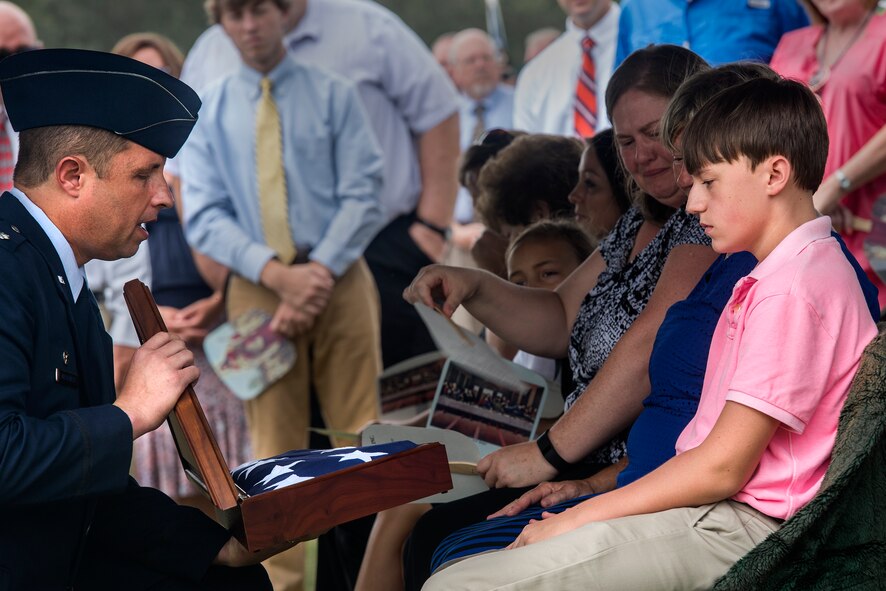U.S. Air Force Lt. Col. Joshua Maskovich, 820th Combat Operations Squadron commander, presents a flag to Hunter Fulp, son of deceased Tech. Sgt. Lee Fulp, July 14, 2015, at the Fellowship Baptist Church in Adel, Ga. Fulp was a member of the 820th COS and served four combat tours in Iraq and Afghanistan as an explosive ordnance disposal specialist. (U.S. Air Force photo by Senior Airman Ryan Callaghan/Released)
