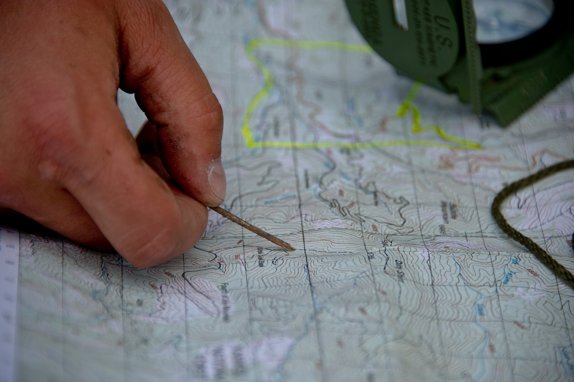 Airman 1st Class Zachary Mikolajczyk, 22nd Training Squadron Survival, Evasion, Resistance and Escape specialist, points at a location on a field training area map June 13, 2015, in the Colville National Forest, Wash. Mikolajczyk showed the S-V-80-A combat survival students how to find their location on a map. The students learned a variety of skills to include fire crafts, water procurement, land navigation and shelter building. (U.S. Air Force photo/Airman 1st Class Nicolo J. Daniello)