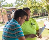 Jeffery Ley, left, 23d Communications Squadron telecommunication specialist, looks at a map blueprint as Rob Storelli, a local outside plant manager, points out where internet-infrastructure construction will take place July 9, 2015, at Moody Air Force Base, Ga. The 23d CS worked with a new provider to bring approximately 600 dorm residents more efficient commercial internet and television service. (U.S. Air Force photo by Airman Greg Nash/Released) 