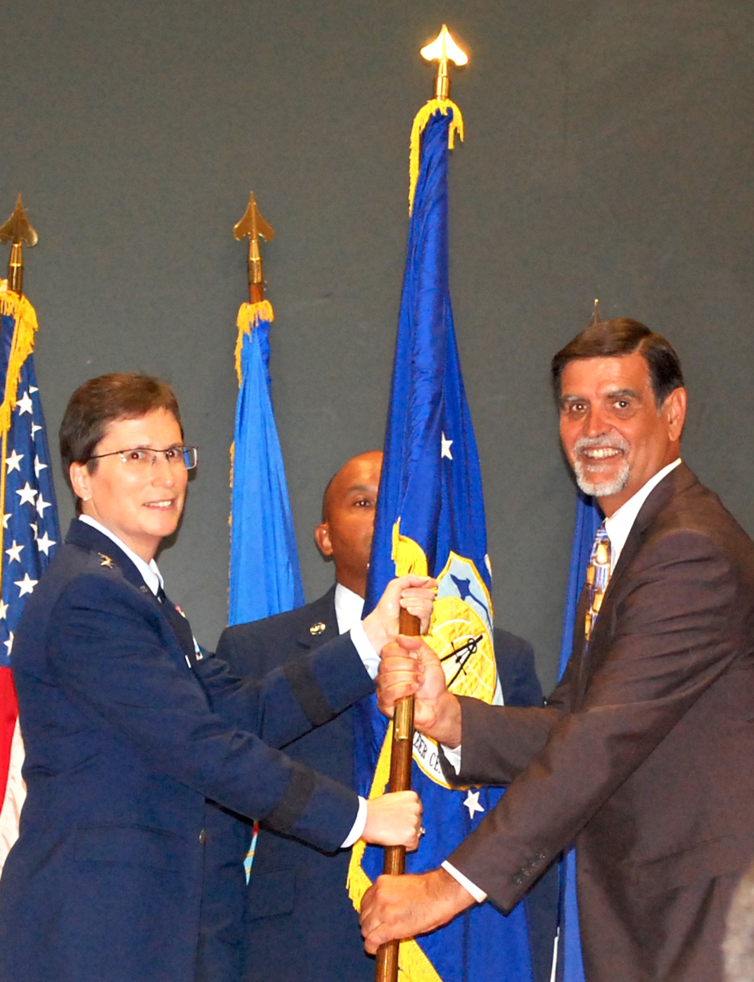 Maj. Gen. Theresa C. Carter, commander of the Air Force Installation and Mission Support Center, passes the unit flag to Randy E. Brown, incoming director of the Air Force Civil Engineer Center during an assumption of leadership ceremony July 16, 2015, at Joint Base San Antonio-Lackland. (U.S. Air Force photo/Susan Scheuer/released)