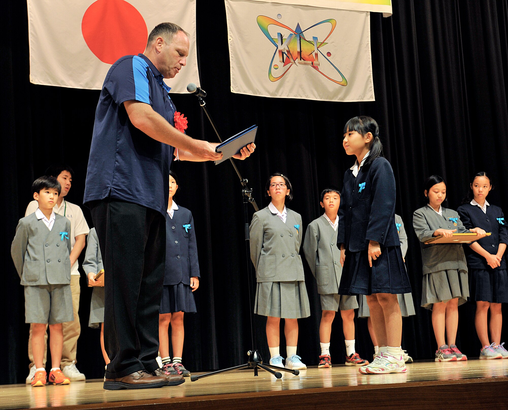 U.S. Air Force Lt. Col. Kieran Keelty, 18th Mission Support Group deputy commander, presents the 18th Wing special award to Moa Maetaba, Yara Elementary School sixth-grade student for her story "Little Red Riding Hood" at the Kadena Rotary Plaza on Okinawa, Japan, July 16, 2015. Fifteen students from elementary and junior high schools of Kadena Town participated in this contest, and each contestant had to memorize their story without notes and within a time limit. (U.S. Air Force photo by Naoto Anazawa) 