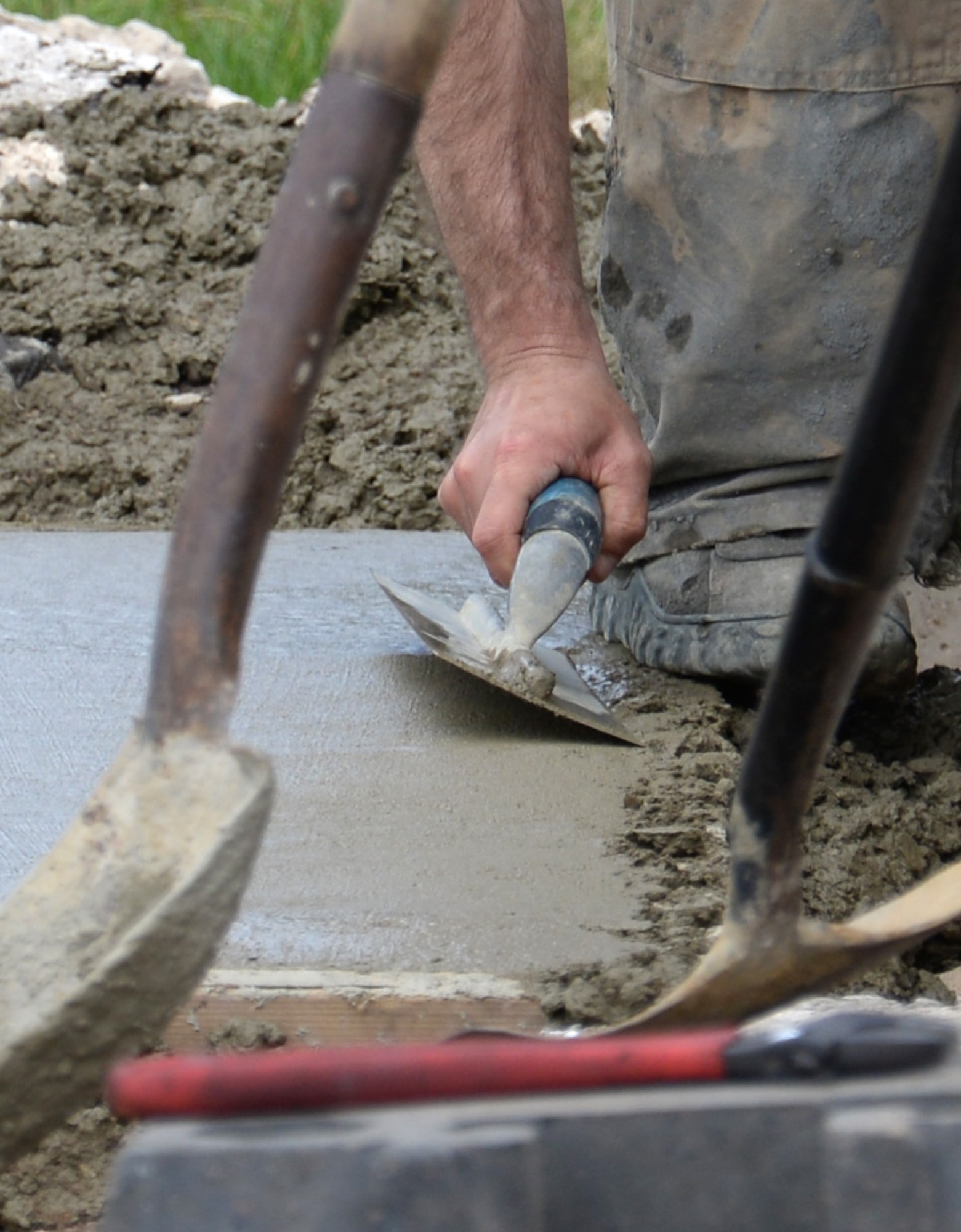 U.S. Air Force Senior Airman Stephen Beasley, 100th Civil Engineer Squadron Pavements and Equipment journeyman from Wakeforest, N.C., skims the surface of the concrete removing any excess water remaining on top and repairing any imperfections of a newly poured sidewalk June 18, 2015, on RAF Mildenhall, England. The final stage was to put a finish on the top for an anti-skid surface and to allow for proper drainage along the newly poured concrete sidewalk. (U.S. Air Force photo by Gina Randall/Released)