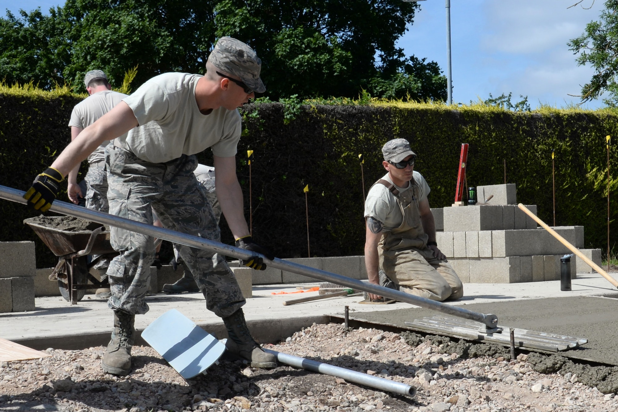 U.S. Air Force Airman 1st Class Gregory Myers, left, 100th Civil Engineer Squadron Pavements and Equipment journeyman from Bakersfield, Calif., uses a bull float to remove any imperfections while leveling concrete June 18, 2015, on RAF Mildenhall, England. The bull float pushes any of the larger aggregate down and brings any of the residual water to the surface. (U.S. Air Force photo by Gina Randall/Released)