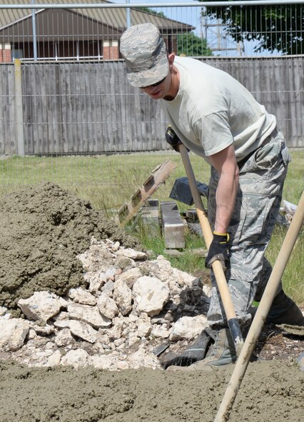 U.S. Air Force Airman 1st Class Gregory Myers, 100th Civil Engineer Squadron Pavements and Equipment journeyman from Bakersfield, Calif., places concrete June 18, 2015, on RAF Mildenhall, England. Myers uses a concrete rake to consolidate the concrete and ensure that it is level across the two preplaced forms to ensure a level surface. (U.S. Air Force photo by Gina Randall/Released)