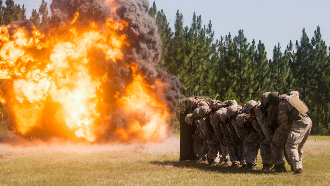 Marines with 2nd Combat Engineer Battalion and 1st Battalion, 8th Marine Regiment crouch behind a protective blanket after detonating a breaching charge during the urban breaching portion of a demolition package at Marine Corps Base Camp Lejeune, North Carolina, July 10, 2015. The demolition package was conducted in preparation for an upcoming deployment, where the two units will be working together in support of Special-Purpose Marine Air-Ground Task Force Crisis Response- Africa. 