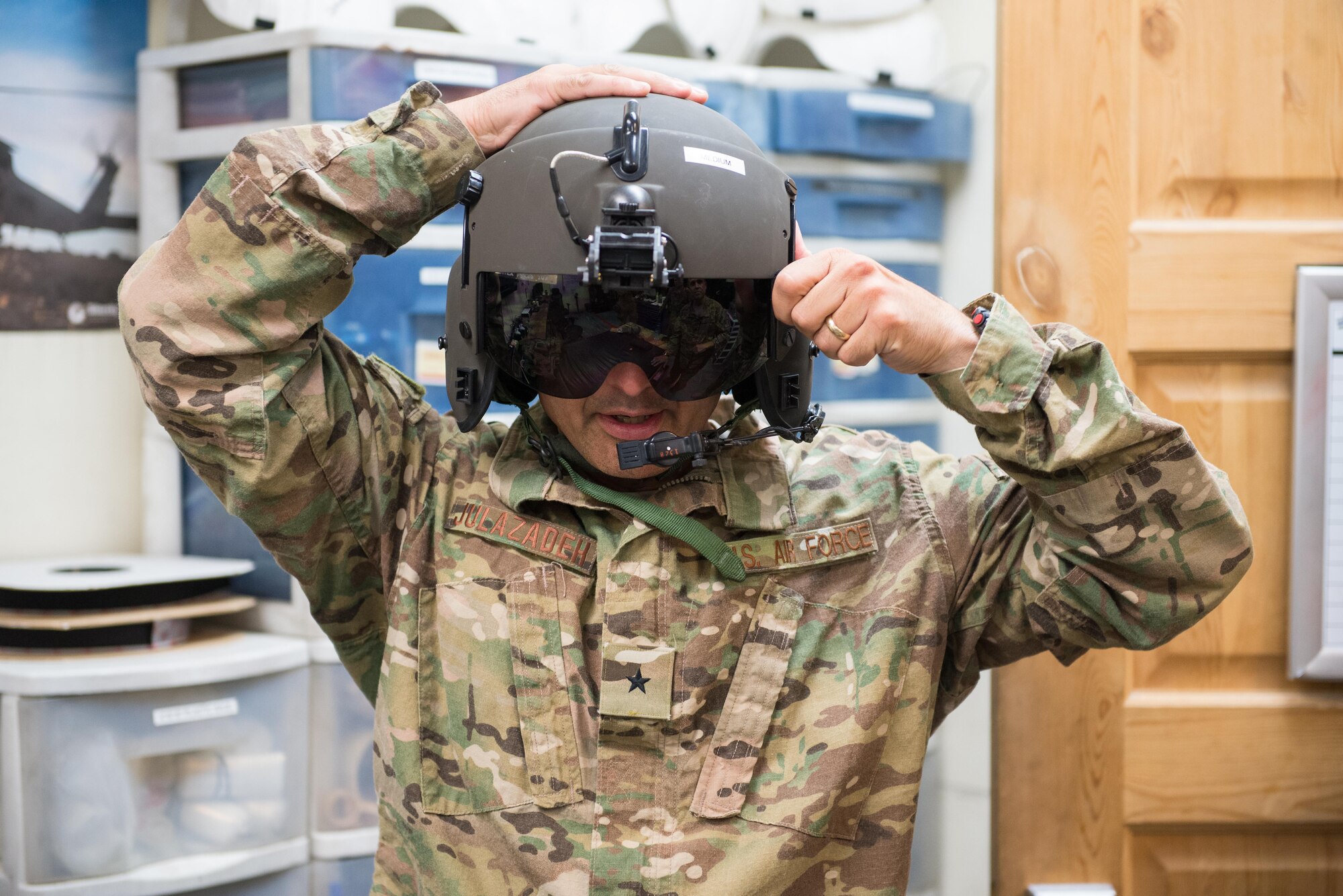 U.S. Air Force Brig. Gen. Dave Julazadeh, 455th Air Expeditionary Wing commander, center, tries on a helmet before going on a mission with the Guardian Angels of the 83rd Expeditionary Rescue Squadron at Bagram Airfield, Afghanistan, July 16, 2015. Julazadeh took part in a training mission with the Aircrew and Guardian Angels of the 83 ERQS to see firsthand how they contribute to the mission in Afghanistan. (U.S. Air Force photo by Tech. Sgt. Joseph Swafford/Released)