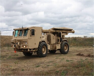 An M1271 Medium Flail Mine Clearing Vehicle is equipped with a rotating flail and 72 chains with fist-sized balls, or hammers, at the end of the chains. As the vehicle drives backwards over the designated area, the flail rotates and the chains dig into the ground tearing mines apart or detonating them. The driver is protected by a deflector shield of armored steel, protecting the both the driver and vehicle against blast pressure and mine fragments.