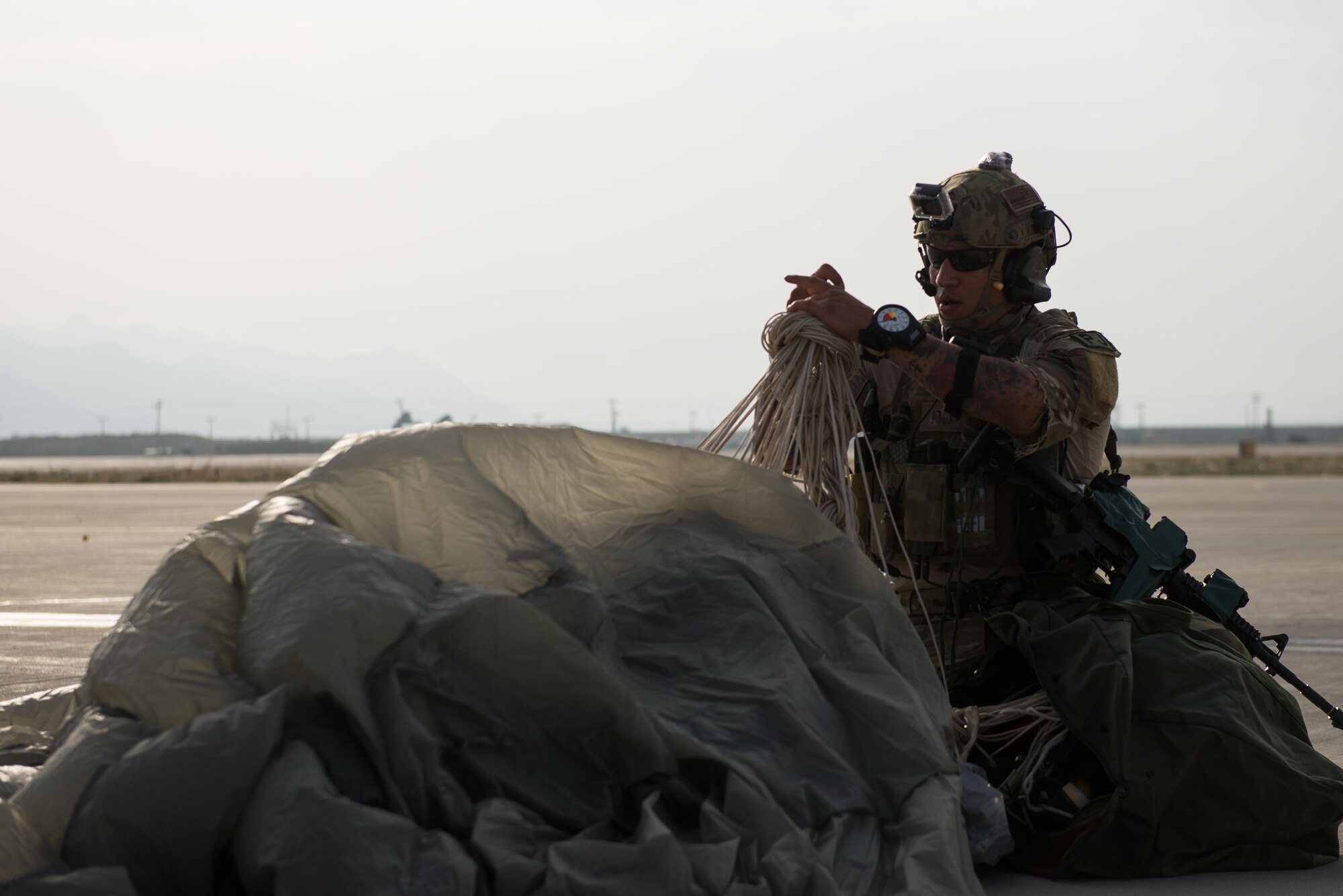 A U.S. Air Force Pararescueman with a Guardian Angel team assigned to the 83rd Expeditionary Rescue Squadron gathers his parachute after landing during High Altitude Low Opening jump training at Bagram Airfield, Afghanistan, July 18, 2015. The 83rd ERQS mission is to rescue, recover, and return American or allied forces in times of danger or extreme duress. (U.S. Air Force photo by Tech. Sgt. Joseph Swafford/Released)