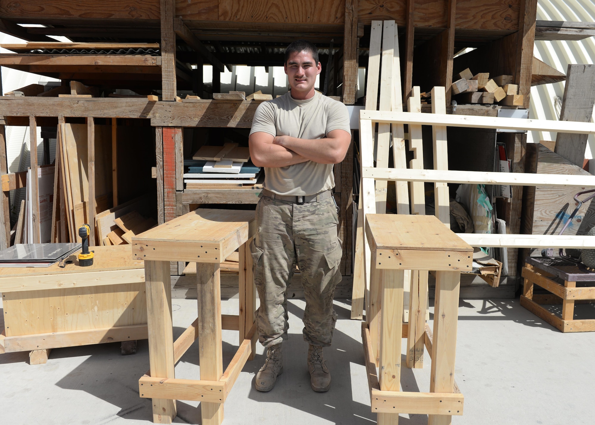 U.S. Air Force Senior Airman Carl Vanlandingham, 455th Expeditionary Civil Engineer Squadron structural journeyman, poses next to two platforms he made, July 16, 2015, at Bagram Airfield, Afghanistan. Vanlandingham builds various projects during duty and on his days off to support the mission here. (U.S. Air Force photo by Senior Airman Cierra Presentado/Released)