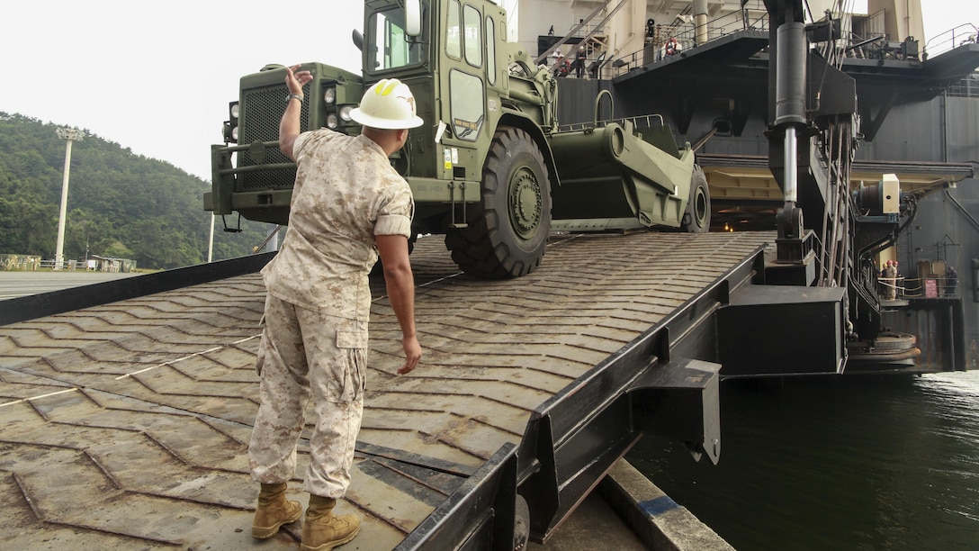 U.S. Marine Corps Gunnery Sergeant Sergio D. Barrios, the Offload Preparation Party (OPP) SNCOIC aboard the USNS 2nd Lt. John P. Bobo, III Marine Expeditionary Force, ground guides a 120-M grader during the MPF Offload of gear and equipment from the Bobo in Chinhae, South Korea, June 13, 2015 in support of Peninsula Express 15. Peninsula Express is one in a series of regularly-scheduled combined, small-unit, tactical training exercises that demonstrates continued dedication to the ROK-U.S. relationship, contributing to the security and stability of the Korean Peninsula and Asia-Pacific region.