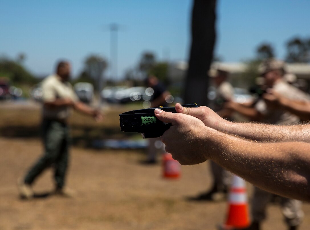 Military police and civilian law enforcement officers with the Marine Corps Air Station Miramar Provost Marshals Office (PMO) practice drawing and aiming the Taser X26 during annual Taser training aboard MCAS Miramar, California, July 15. The training helped familiarize the law enforcement personnel with standardized procedures for employing the weapon. (U.S. Marine Corps photo by Sgt. Brian Marion/Released)
