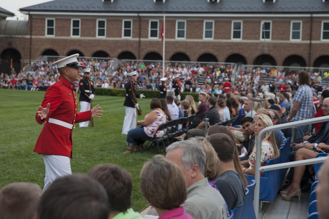 A U.S. Marine Corps crowd educator with the United States Marine Drum and Bugle Corps, speaks to a crowd before an evening parade at Marine Barracks Washington, D.C., July 17, 2015. U.S. Marine Corps Gen. John M. Paxton, assistant commandant of the Marine Corps, was the hosting official for the July 17 evening parade, and the Guest of Honor was Sen. John J. Reed. The Evening Parade summer tradition began in 1934 and features the Silent Drill Platoon, the U.S. Marine Band, the U.S. Marine Drum and Bugle Corps and two marching companies. More than 3,500 guests attend the parade every week. (U.S. Marine Corps Photo by Lance Cpl. Hailey D. Stuart /Released)