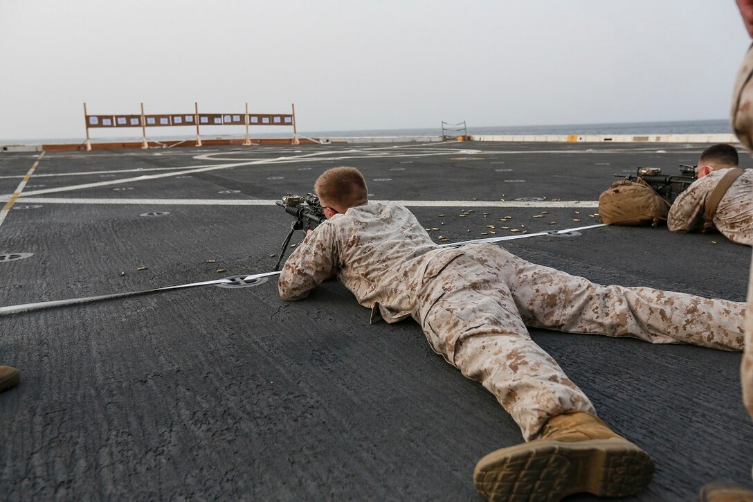 U.S. Marines Lance Cpl. Patrick DeFile, left, fires his weapon to find his battle-sight zero on the flight deck of the amphibious transport dock ship USS Anchorage (LPD 23). DeFile is a scout with Light Armored Reconnaissance Detachment, Battalion Landing Team 3rd Battalion, 1st Marine Regiment, 15th Marine Expeditionary Unit. The Marines with 1st LAR Detachment are members of the ground combat element of the 15th MEU, and embarked aboard the ships of the Essex Amphibious Ready Group, are deployed in support of maritime security operations and theater security cooperation efforts in the U.S. 5th Fleet area of operations. (U.S. Marine Corps photo by Sgt. Steve H. Lopez/ Released)