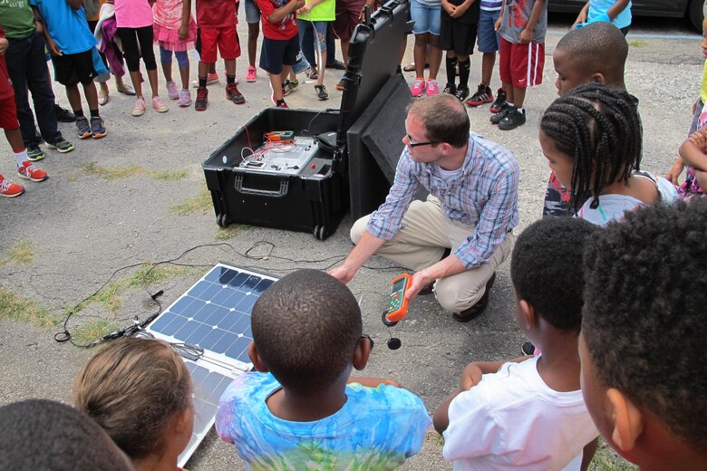 Daniel Tait, kneeling, of the Alabama Center for Sustainable Energy demonstrates how solar panels work during STEM event July 10.