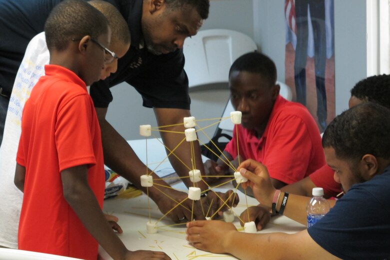Juan Pace,  of the Engineering and Support Center, Huntsville, mentors students during building activity June 19. 