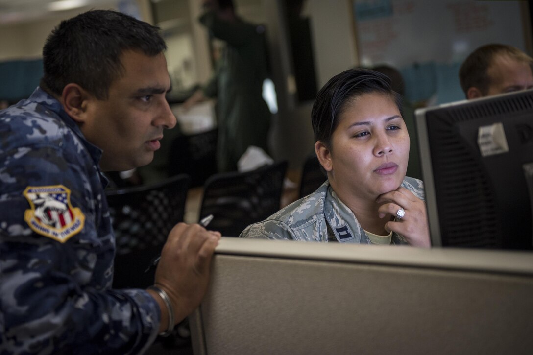 U.S. Air Force Capt. Nicole Vazguez (right), Hawaii Air National Guard command and control duty officer, reviews exercise information with an Australian airman at the 613th Air Operations Center at Joint Base Pearl Harbor-Hickam, Hawaii, as part of Exercise Talisman Sabre 15, July 16, 2015. During the multi-national exercise, U.S. and Australian Airmen teamed up to provide agile, flexible command and control to coalition forces conducting air operations throughout the pacific. (U.S. Air Force photo by Capt. Raymond Geoffroy/Released)