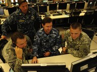 U.S. Air Force Master Sgt. Joshua Samson (left), U.S. Navy Chief Petty Officer Lynn Dangerfield, Royal Australian Air Force Squadron Leader Alan Cooper, and U.S. Army Warrant Officer Trevor Ohnstad, conduct operations  together in the 613th Air Operation Center airspace section, during Talisman Sabre July 16, 2015, at Joint Base Pearl Harbor-Hickam, Hawaii. Talisman Sabre is a biennial exercise that provides an invaluable opportunity for nearly 30,000 U.S. and Australian defense forces to conduct operations in a combined, joint and interagency environment that will increase both countries’ ability to plan and execute a full range of operations from combat missions to humanitarian assistance efforts. (U.S. Air Force photo by Master Sgt. Matthew Mc Govern/Released)
