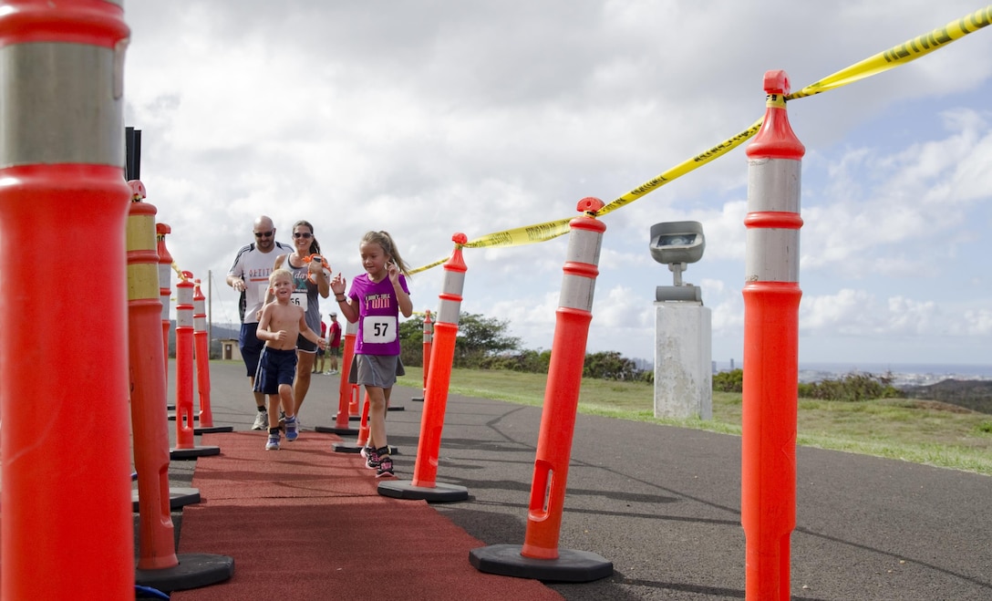 T.C. Clark, a Denver native, and his family reach the finish line at the Camp Smith Grueler 5K race at Bordelon Field aboard Camp H.M. Smith, July 18, 2015. The race, which was part of the Commanding Officer’s Fitness Series, began and ended at Bordelon Field. Participants ran a portion of the race through a trail. Service members aboard Marine Corps Base Hawaii could also earn points for their unit toward the 101 Days of Summer Program by participating in the Grueler. (U.S. Marine Corps photo by Kristen Wong/Released)