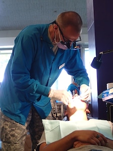 Lt. Col. Craig Colas, a dentist from U.S. Army Dental Activity provides dental treatment at Greater Chenango Cares on July 16, 2015. Greater Chenango Cares is one of the Innovative Readiness Training missions which provides real-world training in a joint civil-military environment while delivering world class medical care to the people of Chenango County, N.Y., from July 13-23. (U.S. Army photo by Sgt. Jennifer Shick/released)