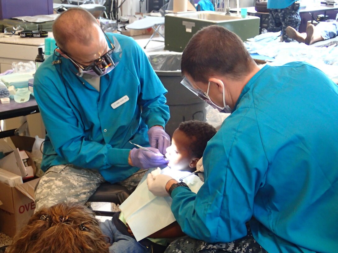 Lt. Col. Craig Colas, right, a dentist from U.S. Army Dental Activity, and Seaman Bryan Igneczi, a hospitalman from EMF Bethesda, provide dental treatment at Greater Chenango Cares on July 17, 2015. Greater Chenango Cares is one of the Innovative Readiness Training missions which provides real-world training in a joint civil-military environment while delivering world class medical care to the people of Chenango County, N.Y., from July 13-23. (U.S. Army photo by Sgt. Jennifer Shick/released)