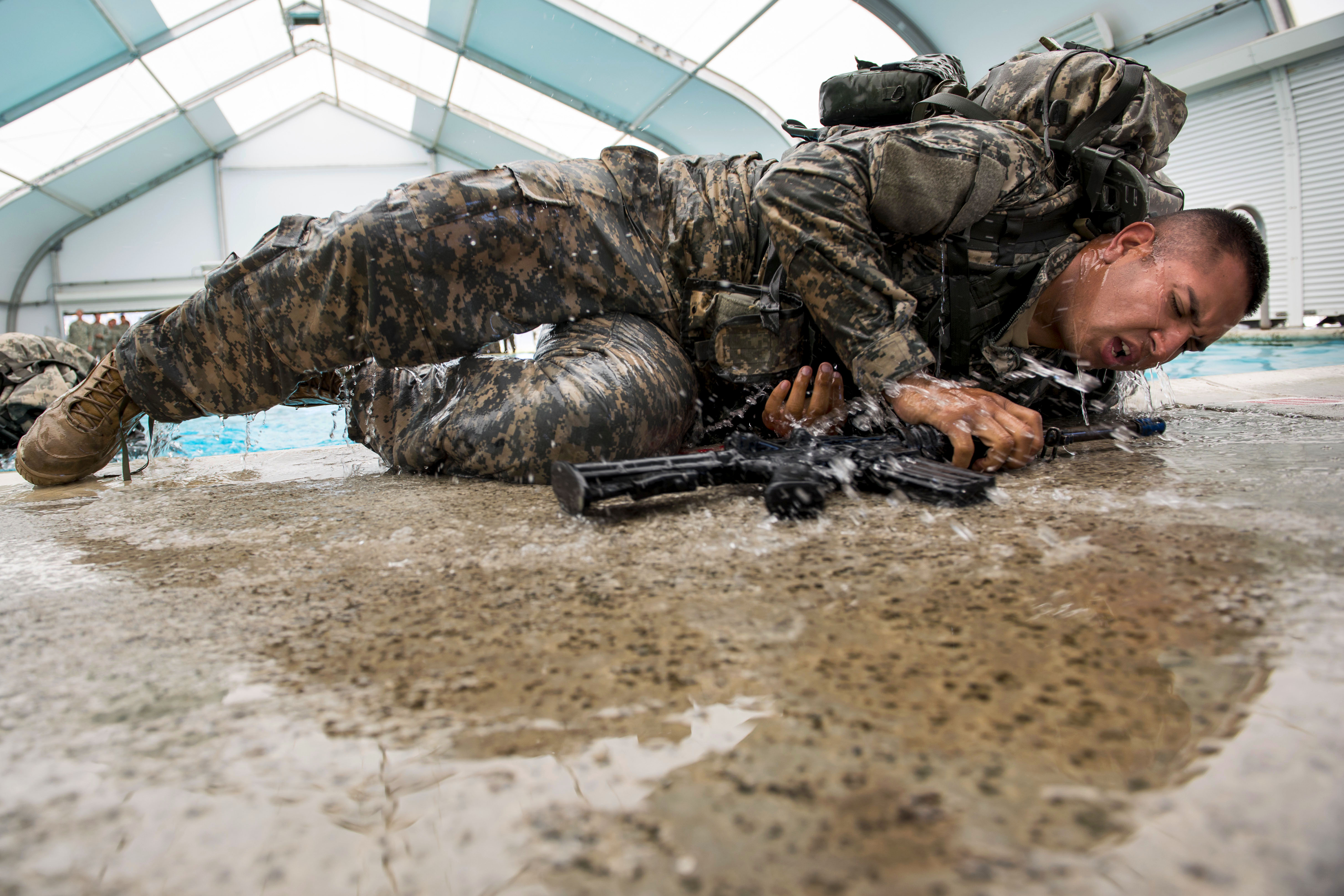 A soldier rolls out of a swimming pool after swimming 25 meters during combat water survival