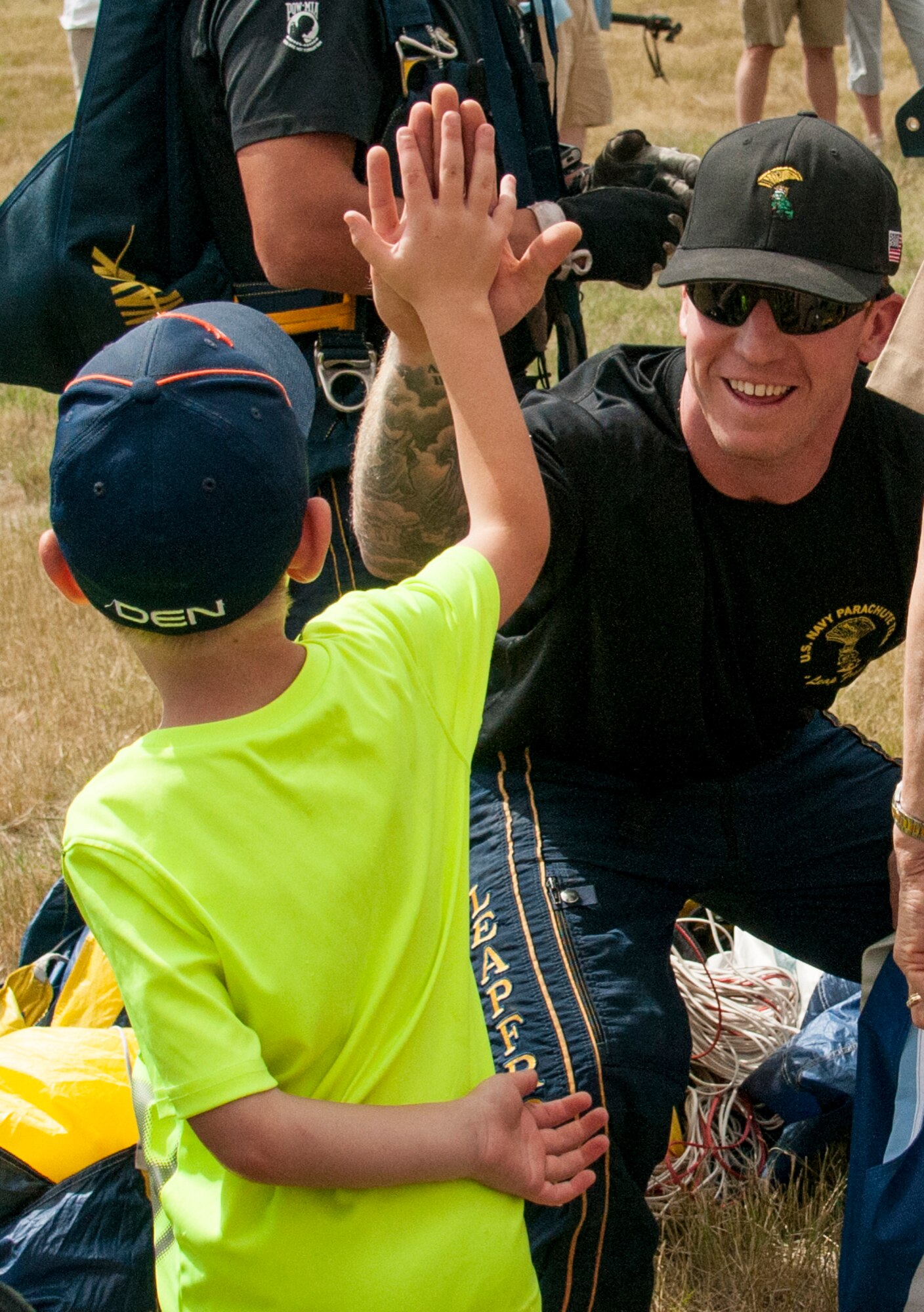 Navy Petty Officer 1st Class Timmy Holland, member of the Leap Frogs, the U.S. Navy parachute team, high fives a child after Holland's parachute landing on F.E. Warren Air Force Base, Wyo., July 18, 2015. The Leap Frogs parachuted onto F.E. Warren for Fort D.A. Russell Days, the base's annual open house. (U.S. Air Force photo by Senior Airman Jason Wiese)