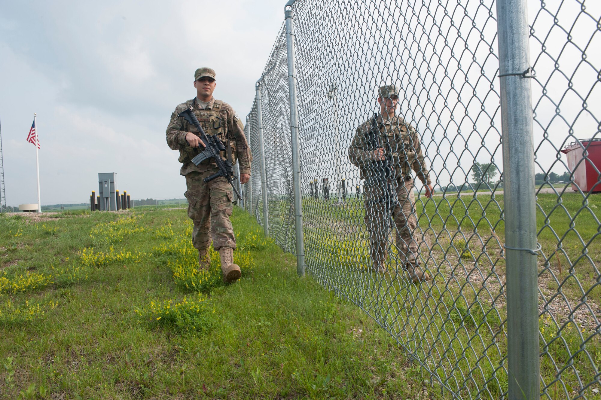 Airmen 1st Class Gibran Hernandez (left), and Brett Payne (right), 91st Missile Security Forces Squadron fire team members, patrol the fence line during shift change-over at the Bravo-01 Missile Alert Facility near Ruso, N.D., July 1, 2015. 91st MSFS working at the MAF are on 12-hour shifts and when the day and night crew swap for change-over, a full patrol of the area outside the MAF is conducted. (U.S. Air Force photo/Senior Airman Stephanie Morris)