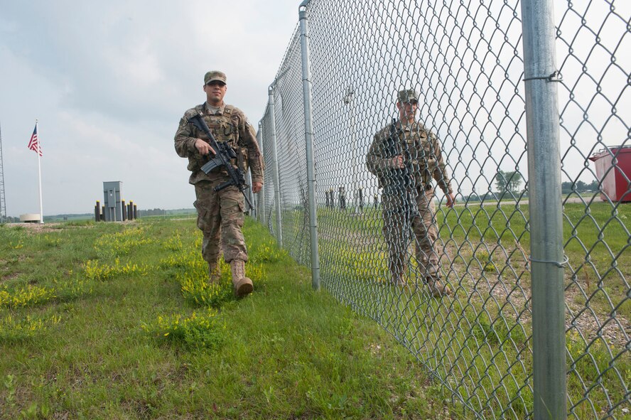 Airmen 1st Class Gibran Hernandez (left), and Brett Payne (right), 91st Missile Security Forces Squadron fire team members, patrol the fence line during shift change-over at the Bravo-01 Missile Alert Facility near Ruso, N.D., July 1, 2015. 91st MSFS working at the MAF are on 12-hour shifts and when the day and night crew swap for change-over, a full patrol of the area outside the MAF is conducted. (U.S. Air Force photo/Senior Airman Stephanie Morris)