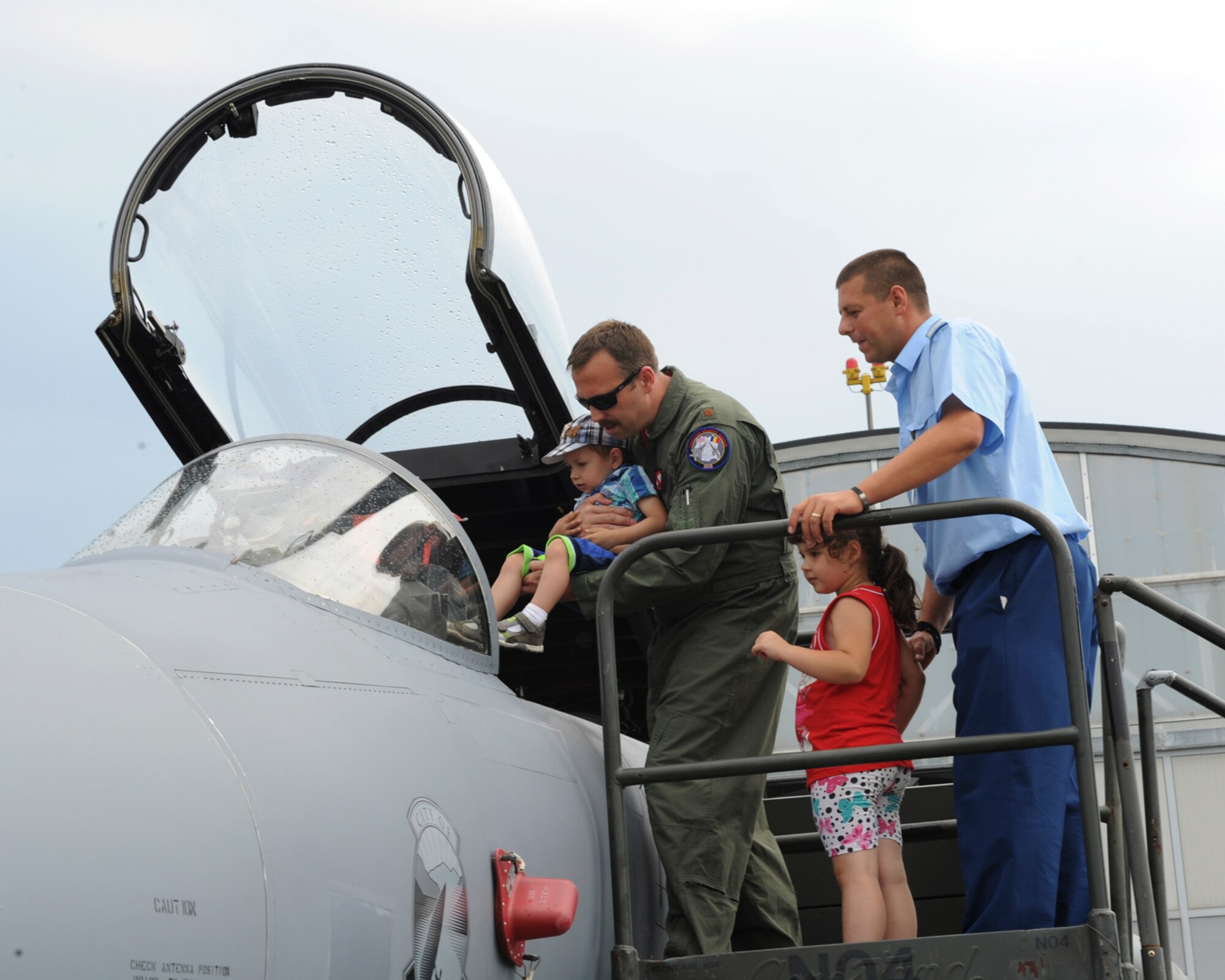A U.S. Air National Guard pilot assigned to the 123rd Expeditionary Fighter Squadron shows the inside of the cockpit of a U.S. Air National Guard F-15C Eagle fighter aircraft to a Romanian air force airman and children during the 2015 Campia Turzii Air Show July 19, 2015, at Campia Turzii, Romania. More than 200 Airmen from the 142nd Fighter Wing, Oregon Air National Guard, Portland, Oregon, trained with the Romanian air force as part of a European theater security package of F-15C Eagles deployed to Romania. (U.S. Air Force photo by Senior Airman Dylan Nuckolls/Released)