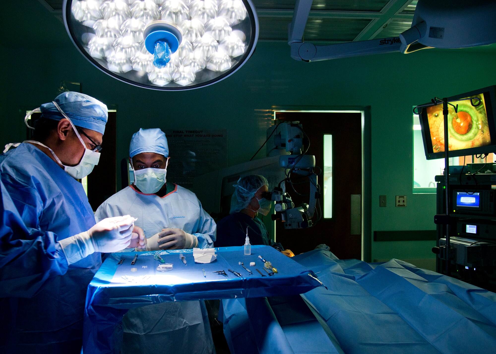 Ophthalmic surgical technicians Senior Airman James Bohannon, 96th Aerospace Medicine Squadron, and civilian contractor Wilfredo Cisneros prepare the new lens for implantation as the doctor performs cataract extraction surgery at Eglin Air Force Base hospital.  During the procedure, the surgeon removes the eye’s cloudy lens known as a cataract and replaces it with a new clear lens implant.  The surgery takes approximately 20 minutes.  The 96th Medical Group performs approximately 150 cataract surgeries per year.  (U.S. Air Force photo/Samuel King Jr.)

