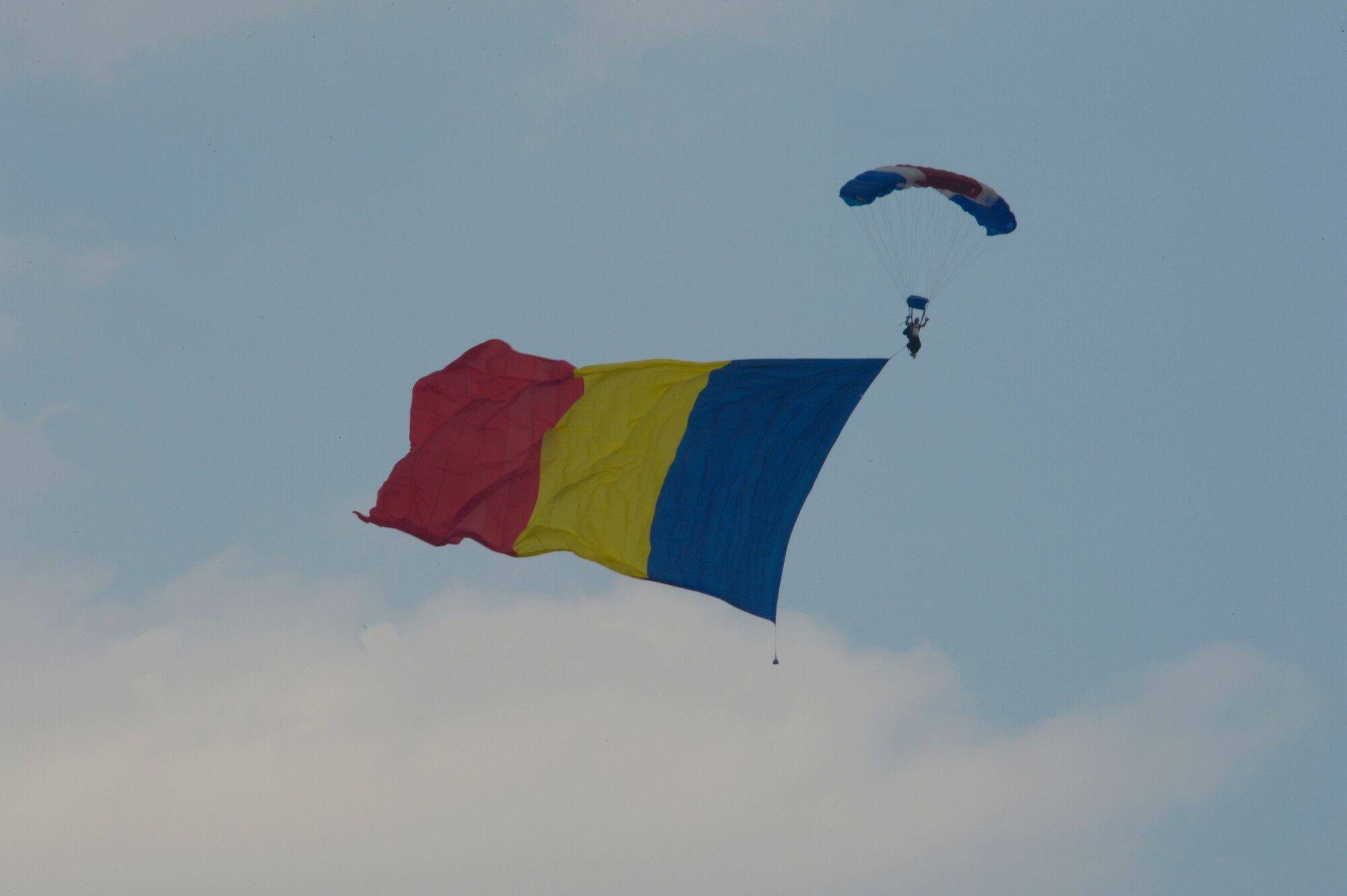 A sky diver parachutes to the ground with the Romanian flag during the 2015 Campia Turzii Air Show July 19, 2015, at Campia Turzii, Romania. The air show celebrated the Romanian air force’s birthday and featured static displays of aircraft, tanks and military equipment. (U.S. Air Force photo by Senior Airman Dylan Nuckolls/Released)