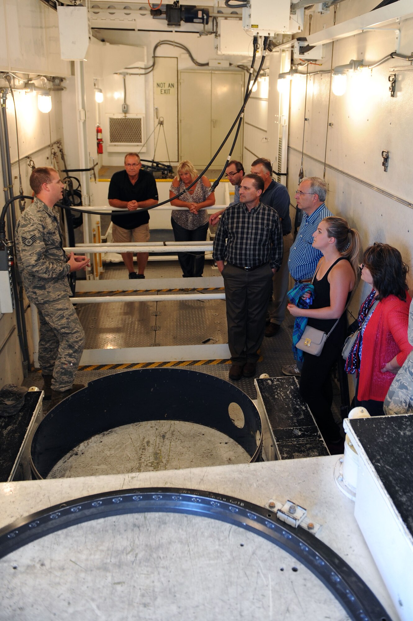 Staff Sgt. Joshua Kulonis, 91st Missile Operations Squadron missile maintenance Instructor, briefs members of the Minot community about the responsibilities of missile maintainers, at the missile trainer facility at Minot Air Force Base, N.D., July 15, 2015. Minot community members toured a missile alert facility as well as a missile trainer facility on base to better understand the 91st Missile Wing’s mission of defending the United States with safe, secure nuclear-capable intercontinental ballistic missiles, ready to immediately put bombs on target. (U.S. Air Force photo/Senior Airman Kristoffer Kaubisch)