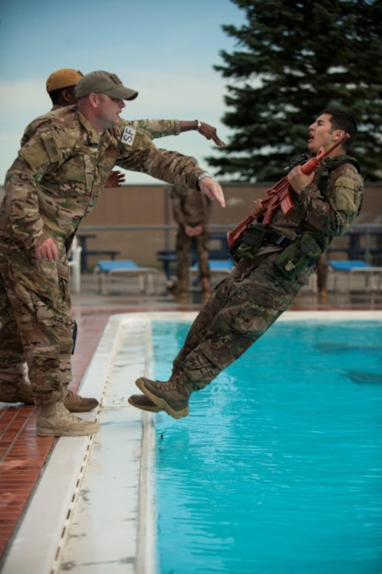 Master Sgt. Todd Boren and Staff Sgt. Gregory Carter, 5th Security Forces Squadron ranger assessment course cadre members, push Staff Sgt. Miguel Garcia, 5th Security Forces member, into the pool for a water confidence exercise during pre-ranger training at Minot Air Force Base, N.D., July 15, 2015. To pass the course, Airmen like Garcia are required to complete a Ranger Physical Assessment, combat water survival assessment, 12 –mile foot march and day and night combined land navigation. (U.S. Air Force photo/Airman 1st Class Christian Sullivan)