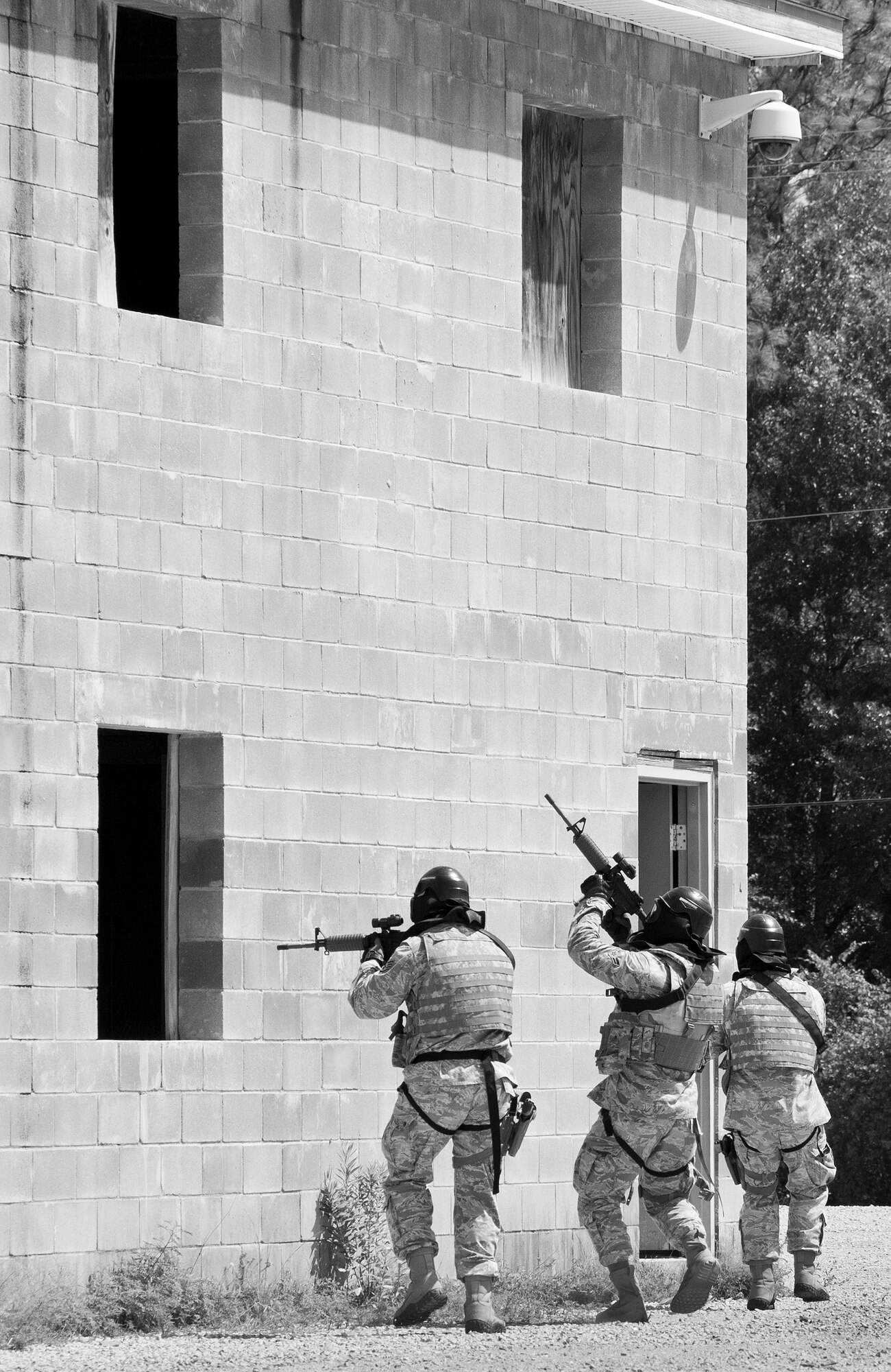 A team of 96th Security Forces Squadron Airmen advance toward a building entrance during a shoot, move and communicate drill in June at Eglin Air Force Base, Fla.  The mandatory training requirement is in addition to annual weapons qualification training.  The exercise consists of Airmen firing simmunition ammo while advancing toward, away from and to the side of a target.  This is followed by a building sweep and clear drill.  The Defenders perform the highly kinetic training at Eglin’s Base Tango range.  The range was previously used for security forces pre-deployment training.  (U.S. Air Force photo/Samuel King Jr.)